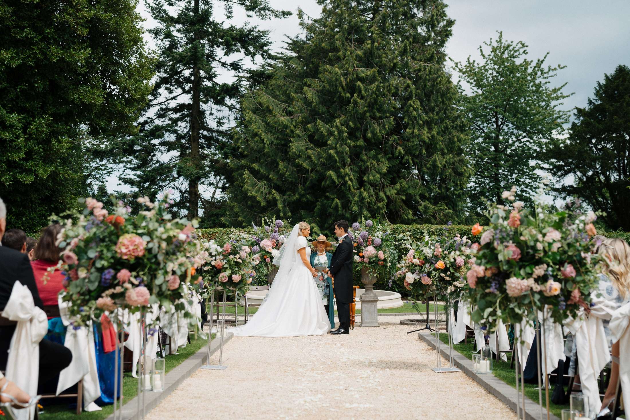 A happy couple saying their vows outside with their guests on either side